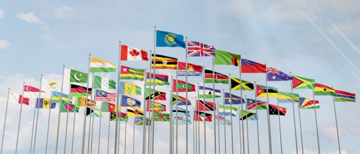 Flags of the Commonwealth flying on flag posts with blue sky behind