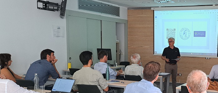 Eugenio Porto speaking to an audience with Adam Smith presentation behind him