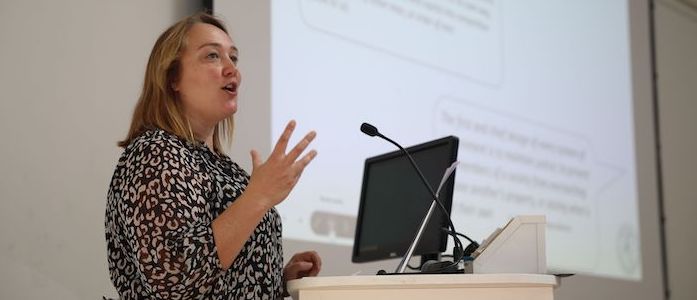 Professor Kat Riach speaking at a podium