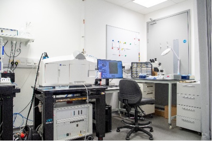 Lab bench with Lightsheet imaging equipment and monitors. Whiteboards on wall behind.