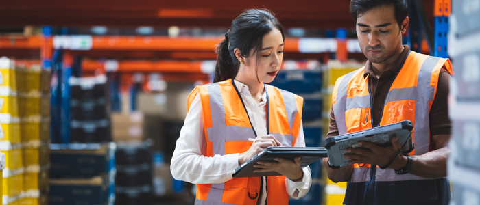 A man and a woman working in a warehouse holding ipads
