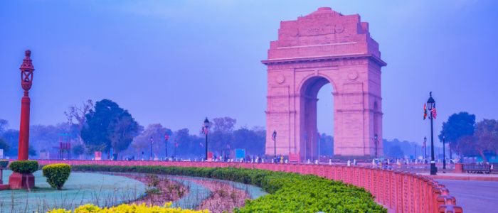 India Gate and foreground lit up in pink by the setting sun
