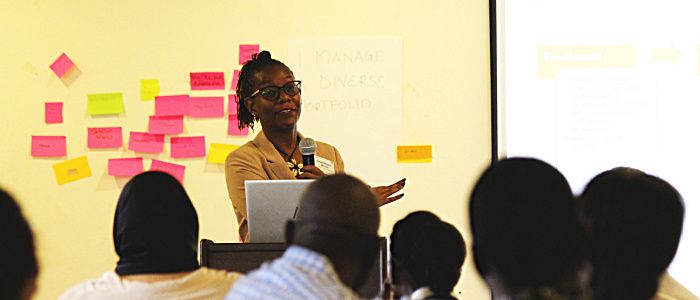 A researcher stands in front of workshop attendees delivering a presentation