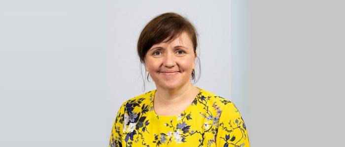 Headshot of Emma Thomson wearing a yellow floral top.