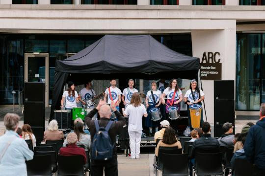 A crowd watch musicians on a marqee stage outside the ARC