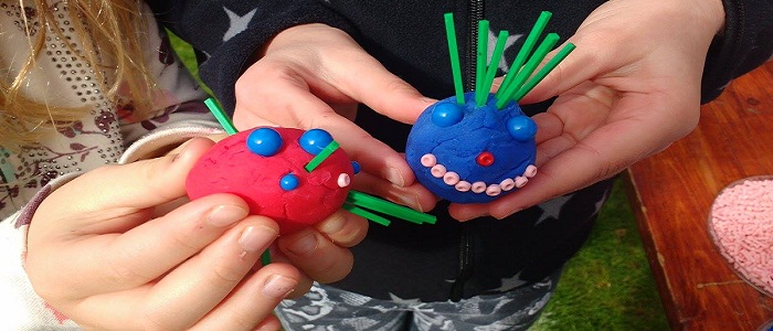Image of hands holding model viruses made with airdough and pegs