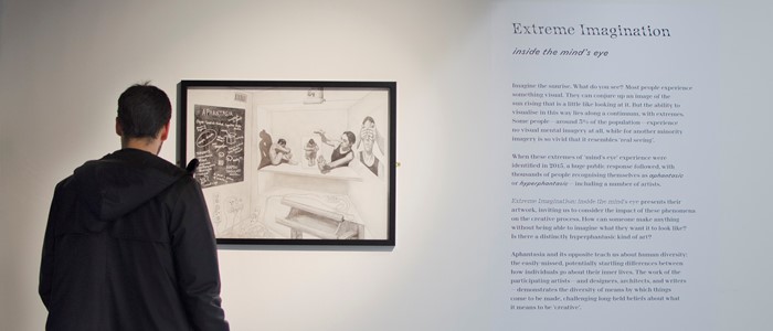 photo of a person in dark clothing in front of a black and white image and black and white text on the wall