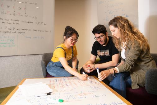 three students sitting around a table problem solving 