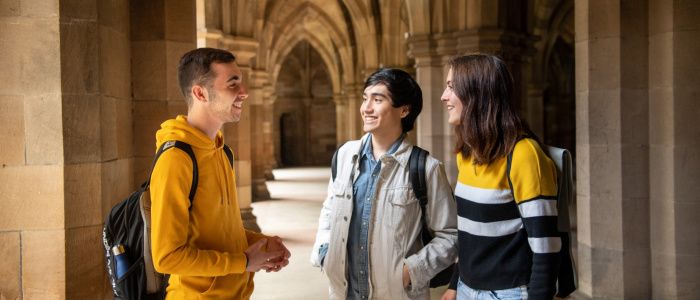 Three students standing talking in the Cloisters