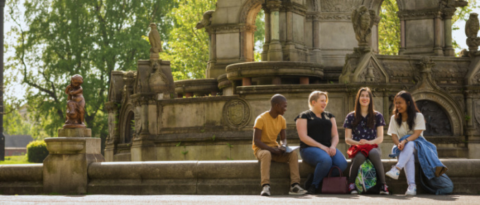 Group of four students sitting in front of the fountain in Kelvingrove Park