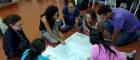 A group of people sitting on the floor examining a map and talking about it