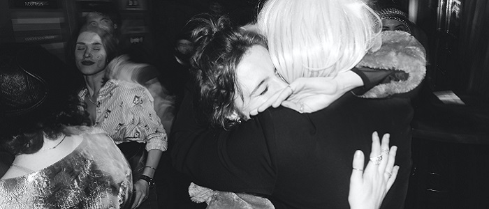 Black and white photo of two people hugging at a party while other people dance around them. Source: https://unsplash.com/photos/2pl_gyZsUGU