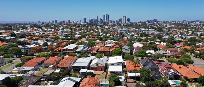 View of the low red roofs of surburban homes with skyscrapers in the distance in the city of Perth in Western Australia. Source: chameleonseye https://www.istockphoto.com/photo/aerial-landscape-view-of-perth-western-australia-gm1289818542-385380862