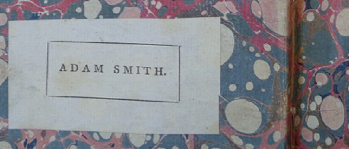 A label with the text ' ADAM SMITH' pasted into the blue and red marbled inside cover of a book