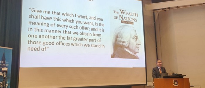 Photo of Professor Zhiwu Chen at a podium and a slide behind him with an image of Adam Smith and text. Source: Ghassan Moazzin on Twitter https://twitter.com/GhassanMoazzin/status/1639188298508931073?s=20